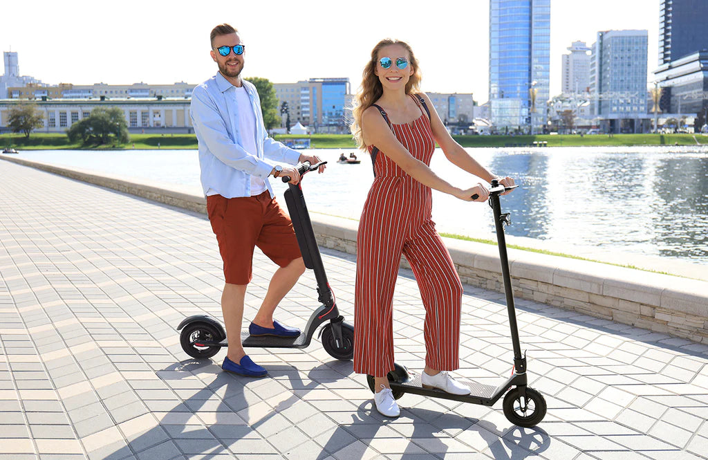 En kvinna och en man ståendes på varsin elsparkcykel i stadsmiljö